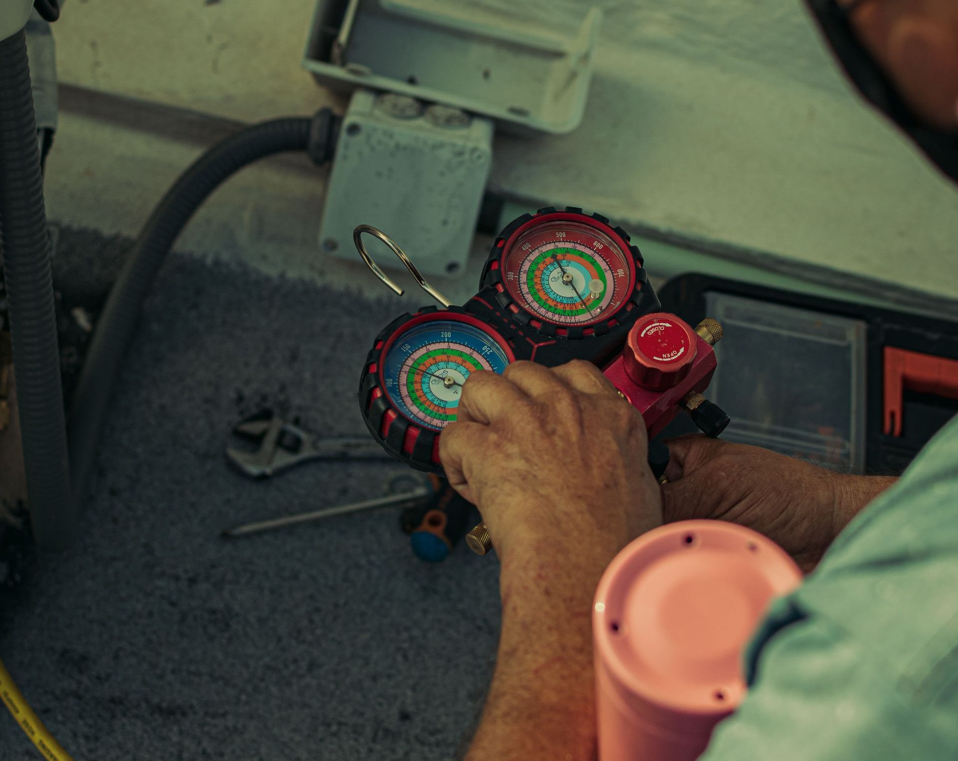 Professional technician adjusting a refrigerant manifold gauge for air conditioning maintenance.